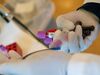 A phlebotomist takes blood samples for testing a recovered COVID-19 patient.