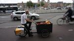 A cargo bike pedals past Amsterdam's Central Station