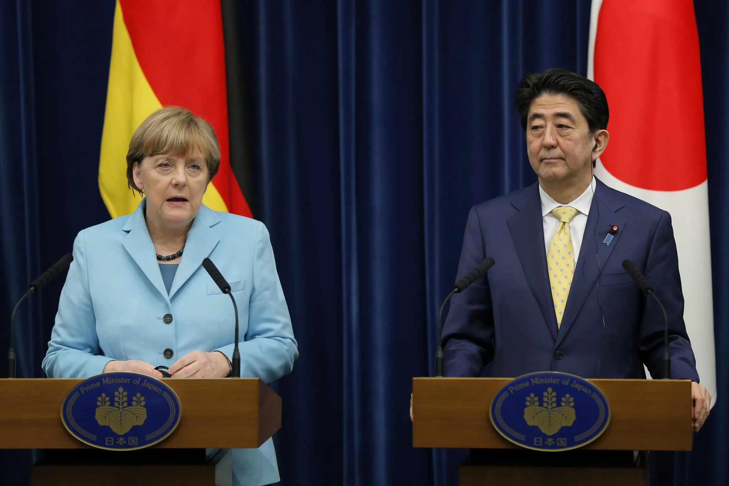 Angela Merkel, Germany's Chancellor, left, speaks as Shinzo Abe, Japan's prime minister, looks on during a news conference in Tokyo, Japan, on Monday, March 9, 2015.
