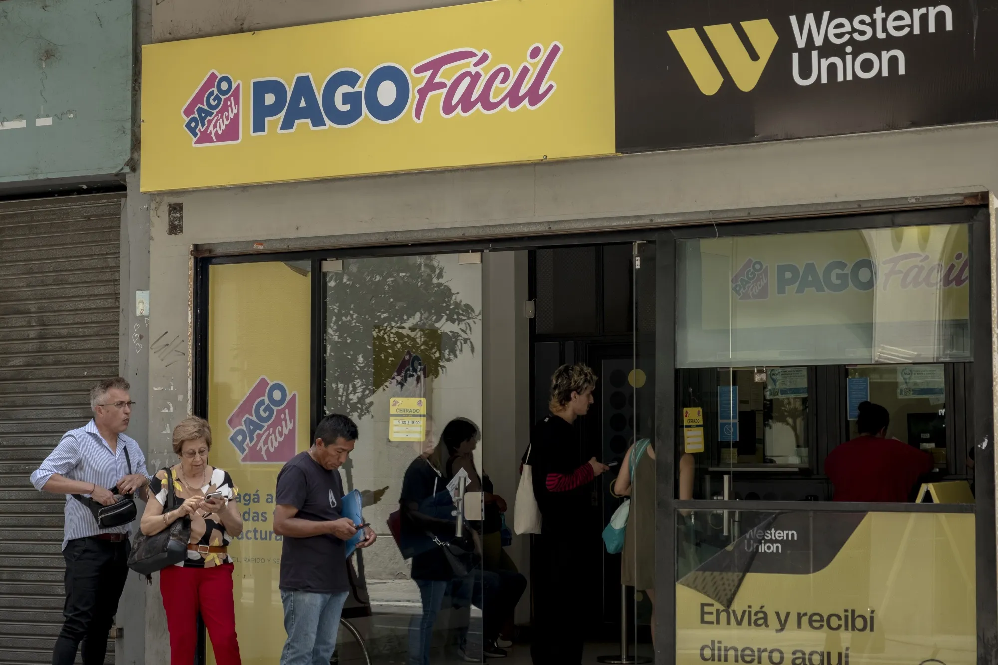 Customers wait in line at a Western Union in Buenos Aires, Argentina.&nbsp;The government of Javier Milei won’t lift currency controls immediately after taking office on Dec. 10.