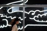 A pedestrian walks past a window display at a Lacoste SA store in Kawasaki, Japan.