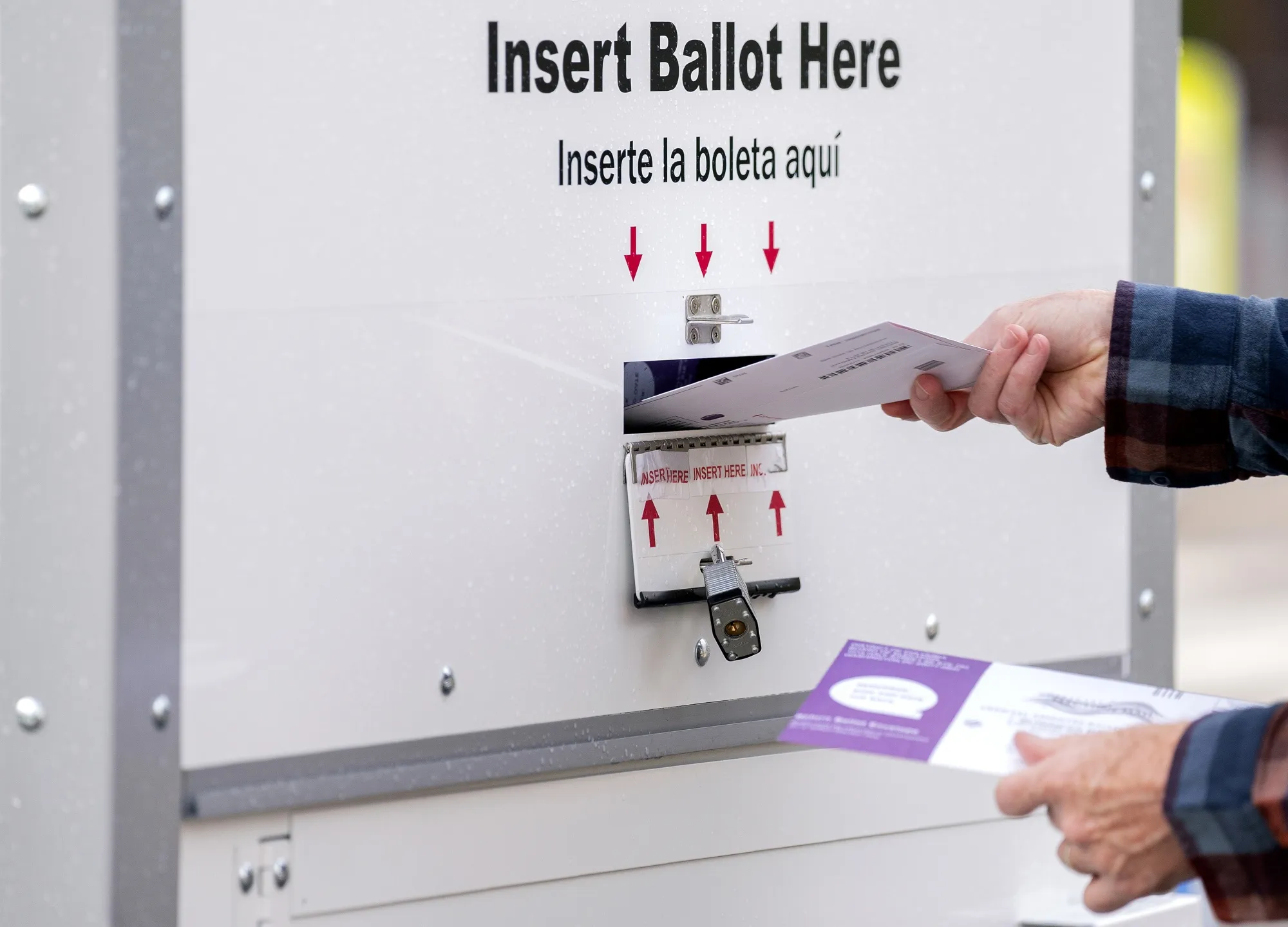 A voter deposits a ballot into an Official Ballot Drop Box in Washington.