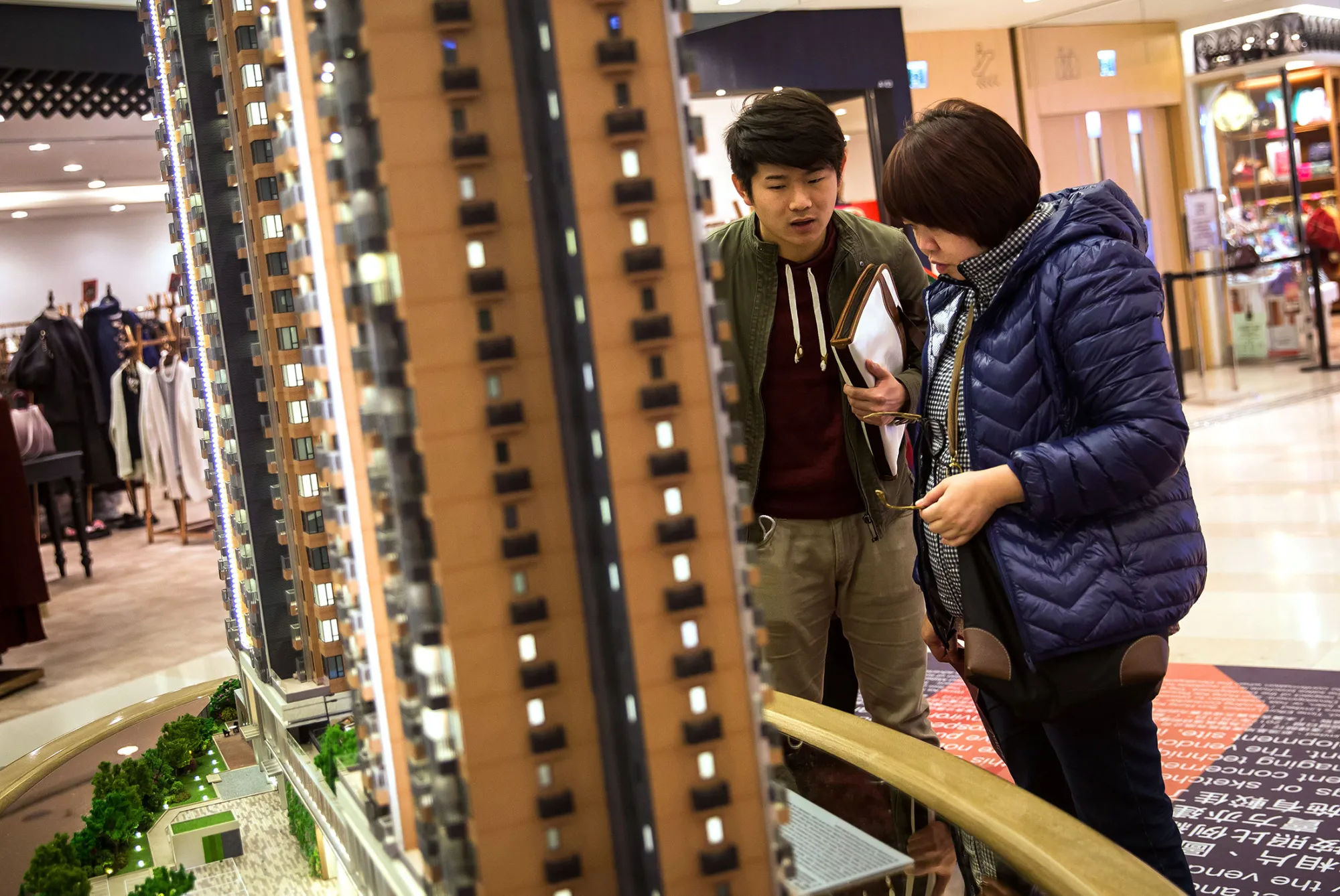 An estate agent, left, speaks to a potential buyer while they look at a model of Park Vista, a residential property developed by Sun Hung Kai Properties Ltd., at a sales exhibition in Hong Kong, China, on Wednesday, Feb. 3, 2016. Hong Kong is seeing negative-equity mortgages for the first time since September 2014.
