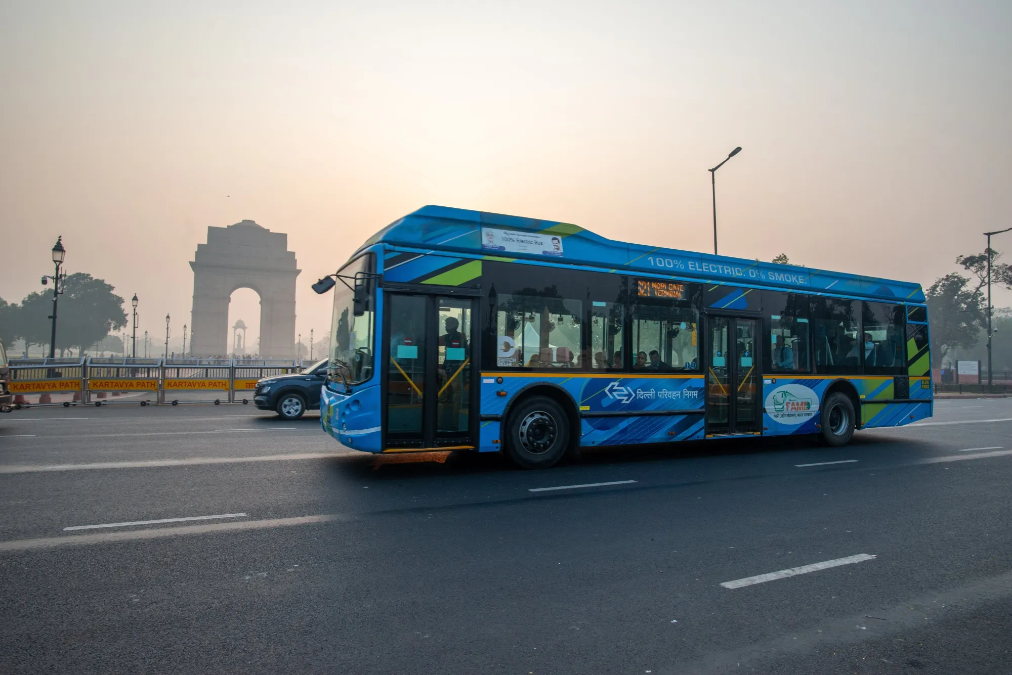 An electric bus navigating through the smog near India Gate.