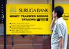 A man talks on his mobile phone outside of a branch of the Suruga Bank in Tokyo.