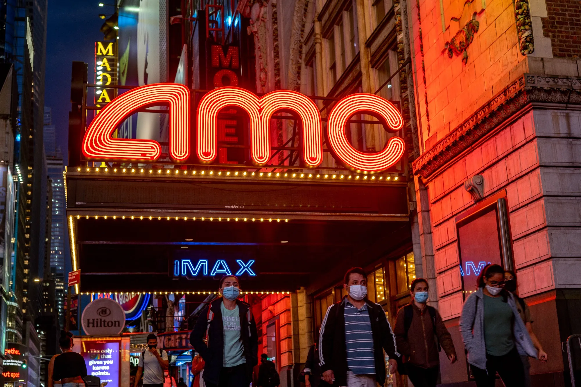Pedestrians pass in front of an AMC movie theater in the Times Square neighborhood of New York.