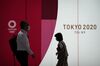 Pedestrians wearing protective masks walk past an advertisement for the now-postponed Tokyo 2020 Olympic and Paralympic Games in Tokyo, Japan, on Monday, June 8, 2020.