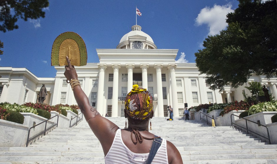 Face off: Abayomi Goodall waves a fan during a march at the Alabama State Capitol and Statehouse in Montgomery.