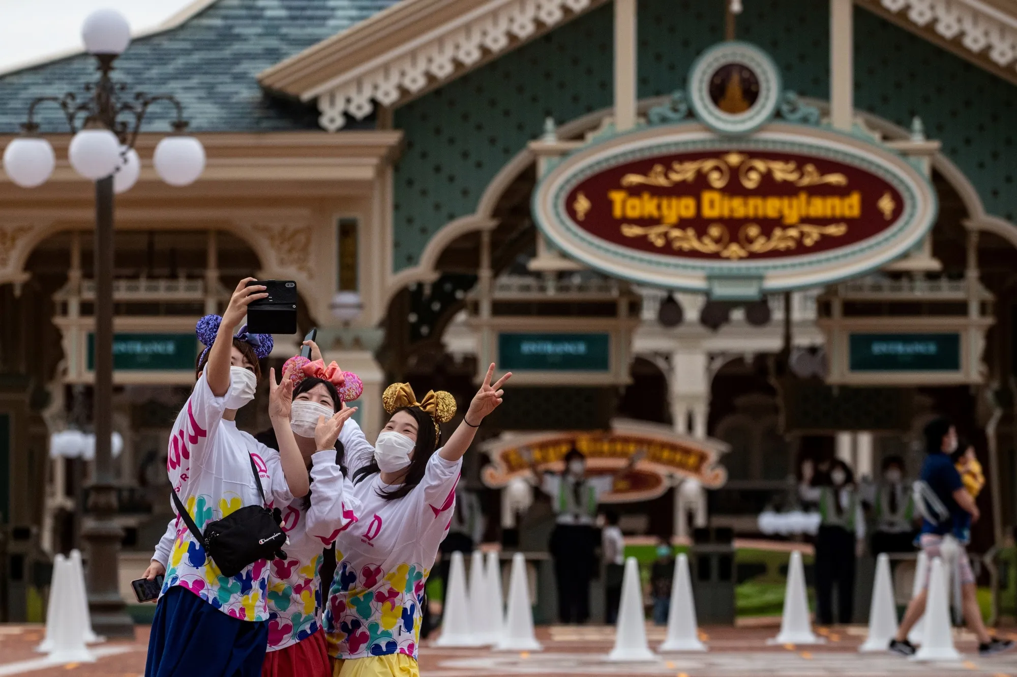 Visitors wearing face masks take photos outside Tokyo Disneyland during the reopening day, near Tokyo on July 1.