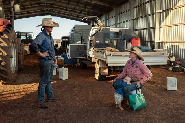 Molly and Tom Sutton, with their son, Wally chat under shed in front of their farm equipment.. 