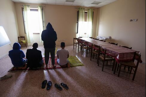 A group of refugees pray at the Palazzo Condo