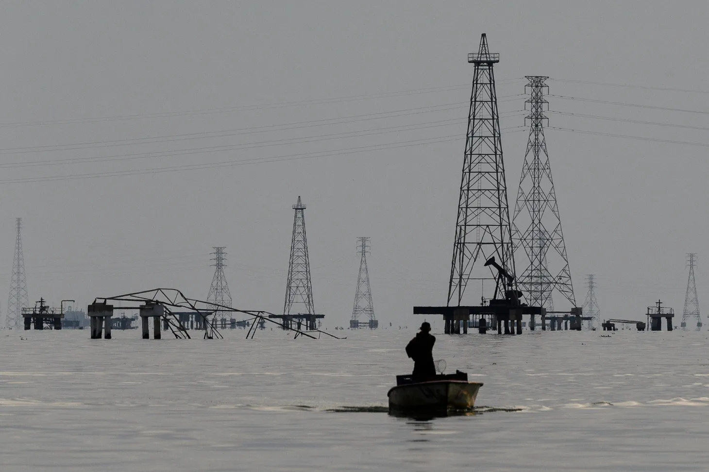 A fishermen in front of Petroleos de Venezuela SA oil rigs on Lake Maracaibo in Cabimas, Zulia state, Venezuela.