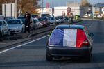A French national flag hangs from a vehicle as it moves alongside stationary traffic during a protest against fuel costs near Rodez on Nov. 17.