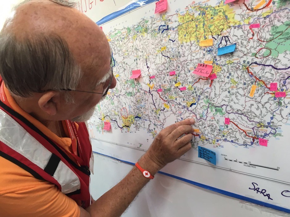 A relief worker checks road conditions on a map of Puerto Rico during aid distribution planning in San Juan.
