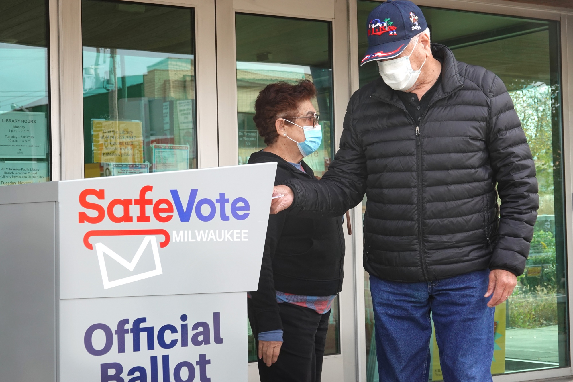 Residents drop mail-in ballots in an official ballot box outside of a library in Milwaukee on Oct. 20, 2020.