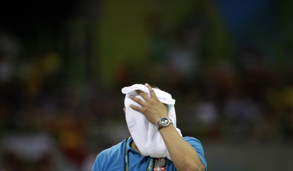 The coach of Poland's Olympic handball team wipes sweat from his face.