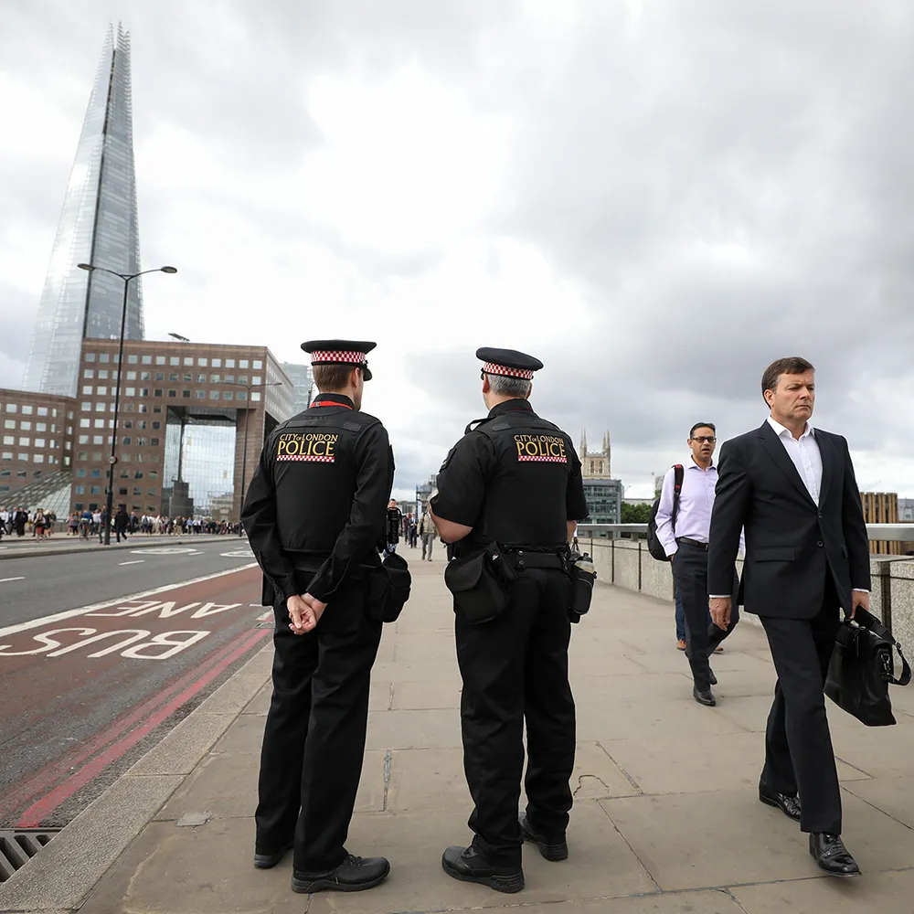 City of London Police officer stand on London Bridge as commuters walk past, following Saturday night's terror attack, in London, U.K., on Monday, June 5, 2017. Police are stepping up drills and security on the streets as the challenge facing them continues to shift.
