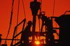 Oil and gas drilling workers on rig, silhouette, sunrise