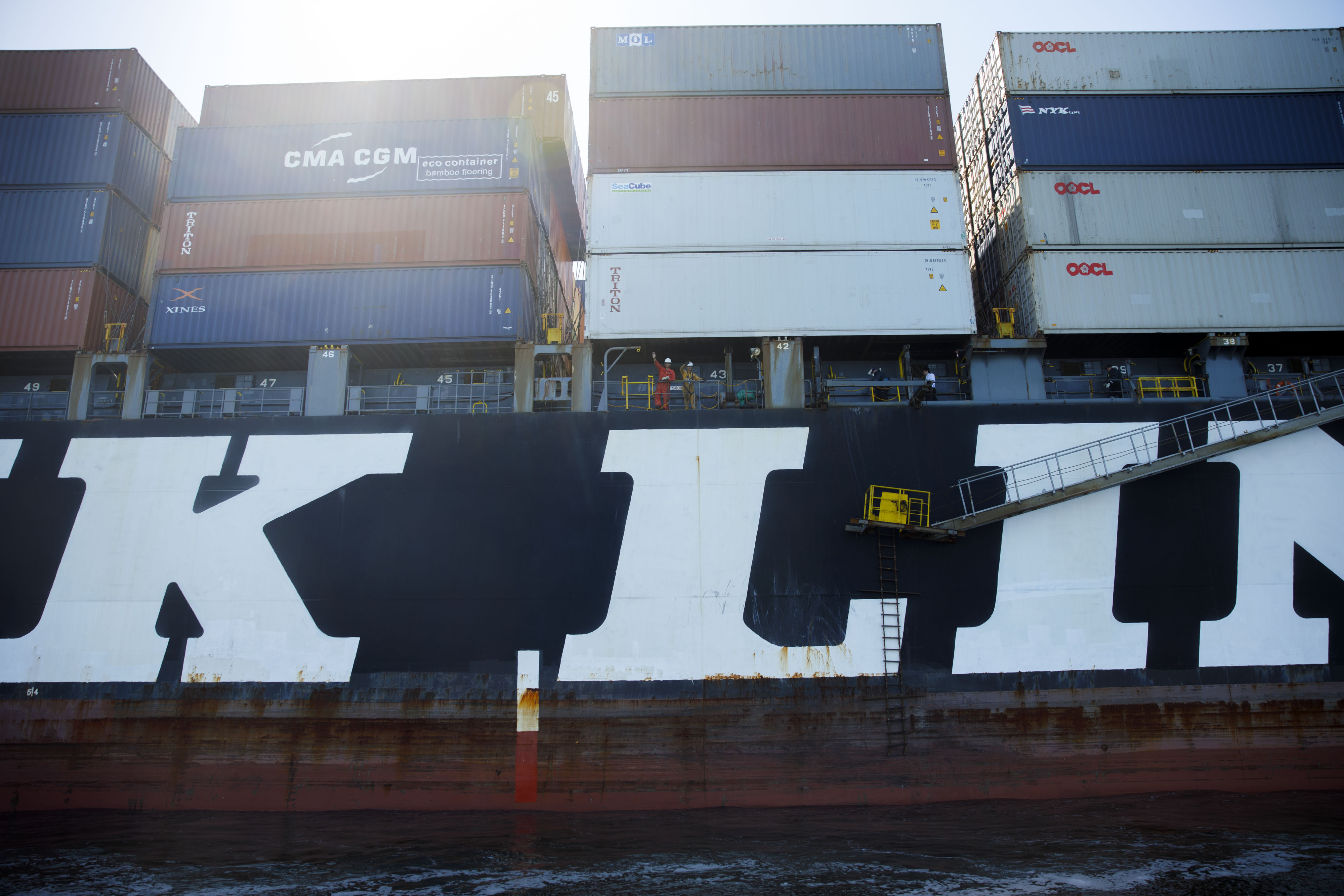 Crew members wave from the NYK Demeter container ship outside the Port of Los Angeles in Los Angeles, California, U.S., on Wednesday, March 28, 2018.&nbsp;