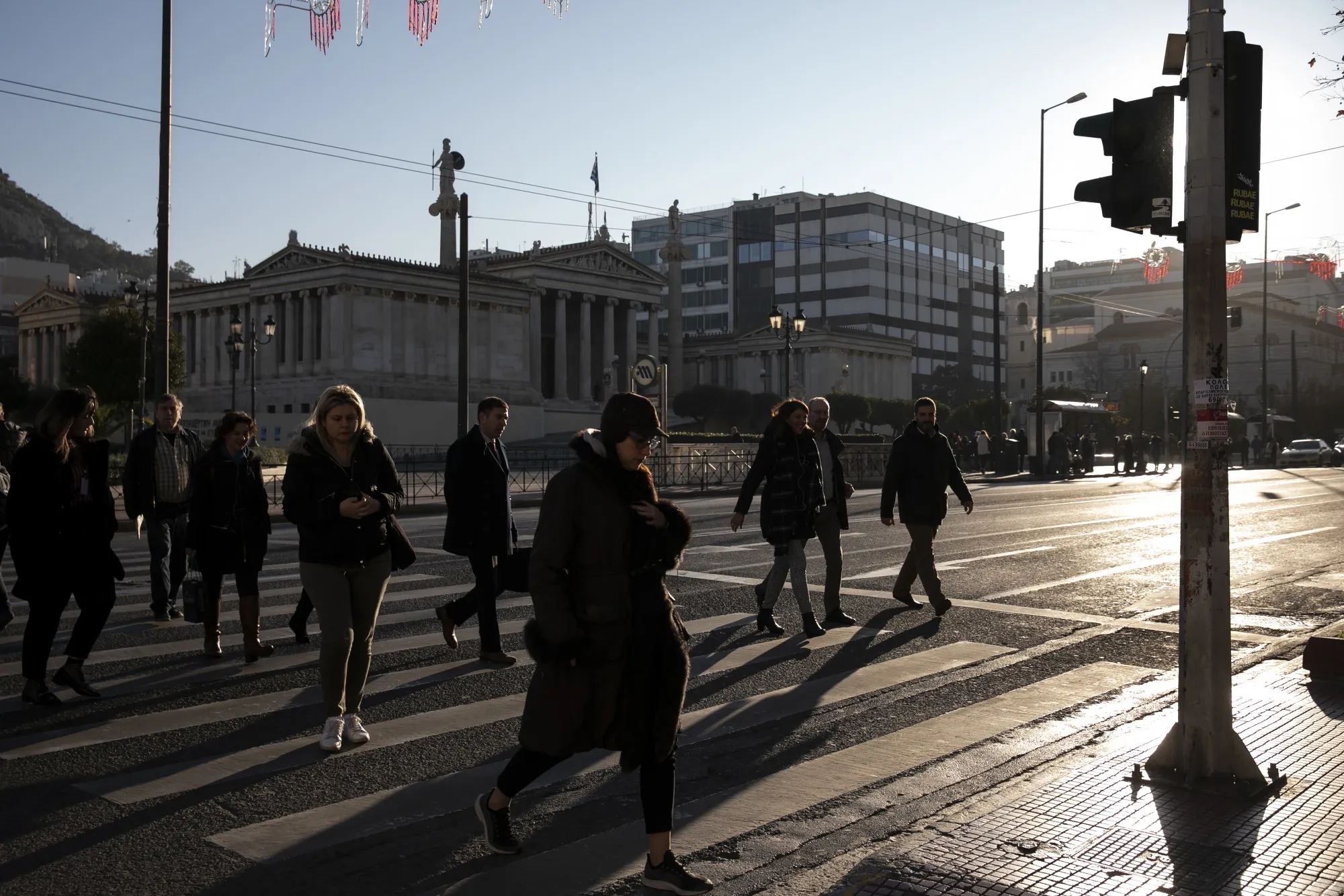 Pedestrians walk across a street crossing in Athens.