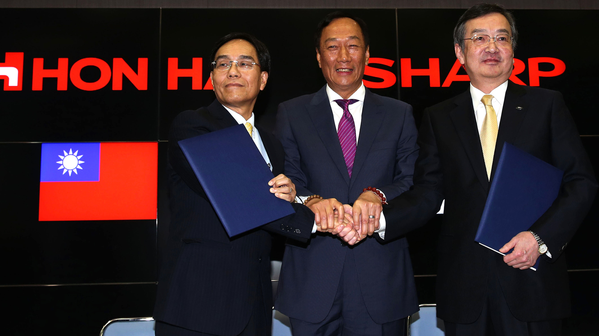 Tai Jeng-wu, vice president of Foxconn Technology Group, left, shakes hands with Billionaire Terry Gou, chairman of Foxconn Technology Group, center, and Kozo Takahashi, president of Sharp Corp., during a news conference in Osaka, Japan, on Saturday, April 2, 2016.
