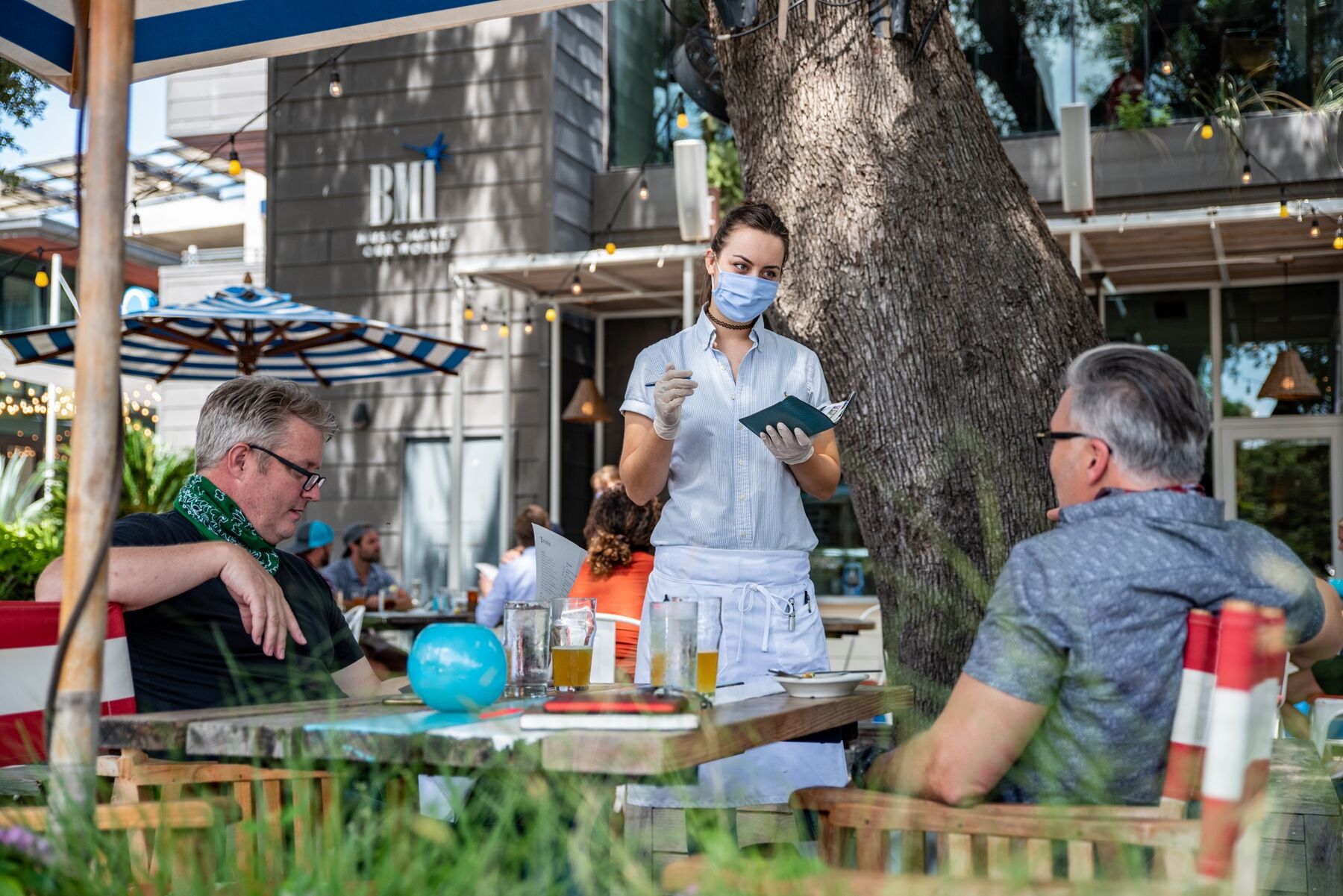 A server wearing a protective mask takes an order at a restaurant in Austin.