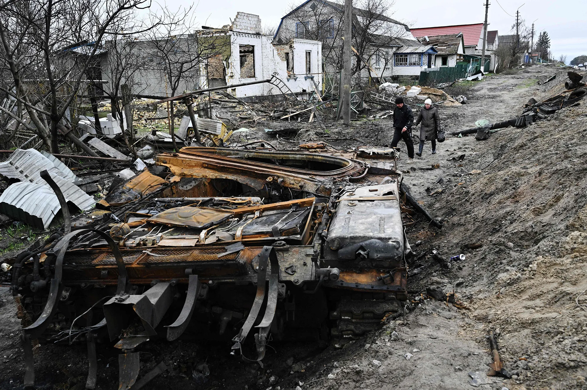 Locals walk amid debris of a charred Russian tank in the village of Zalissya, northeast of Kyiv, on April 19.