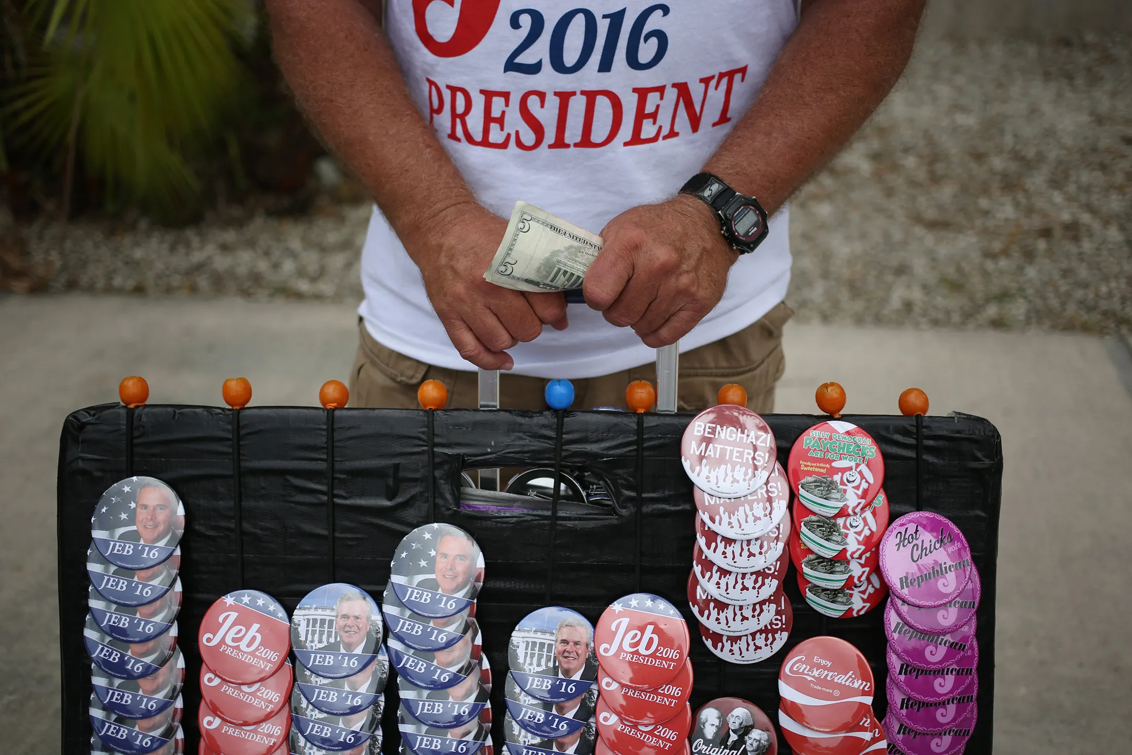 A vendor holds money while selling buttons and t-shirts outside an event where Jeb Bush announced he will seek the 2016 Republican presidential nomination in Miami, Fla., on June 15, 2015.
