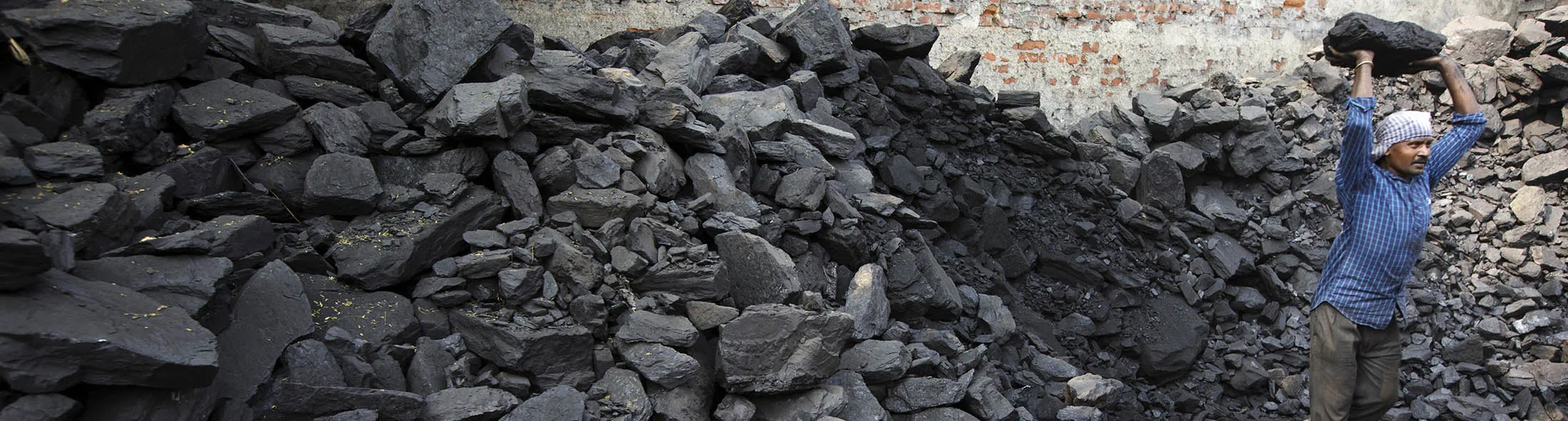 A worker lifts a lump of coal while loading a truck at a wholesaler in New Delhi, India, on Wednesday, Nov. 5, 2014. Prime Minister Narendra Modi is seeking to end a four-decade-old government monopoly on mining and selling coal.
