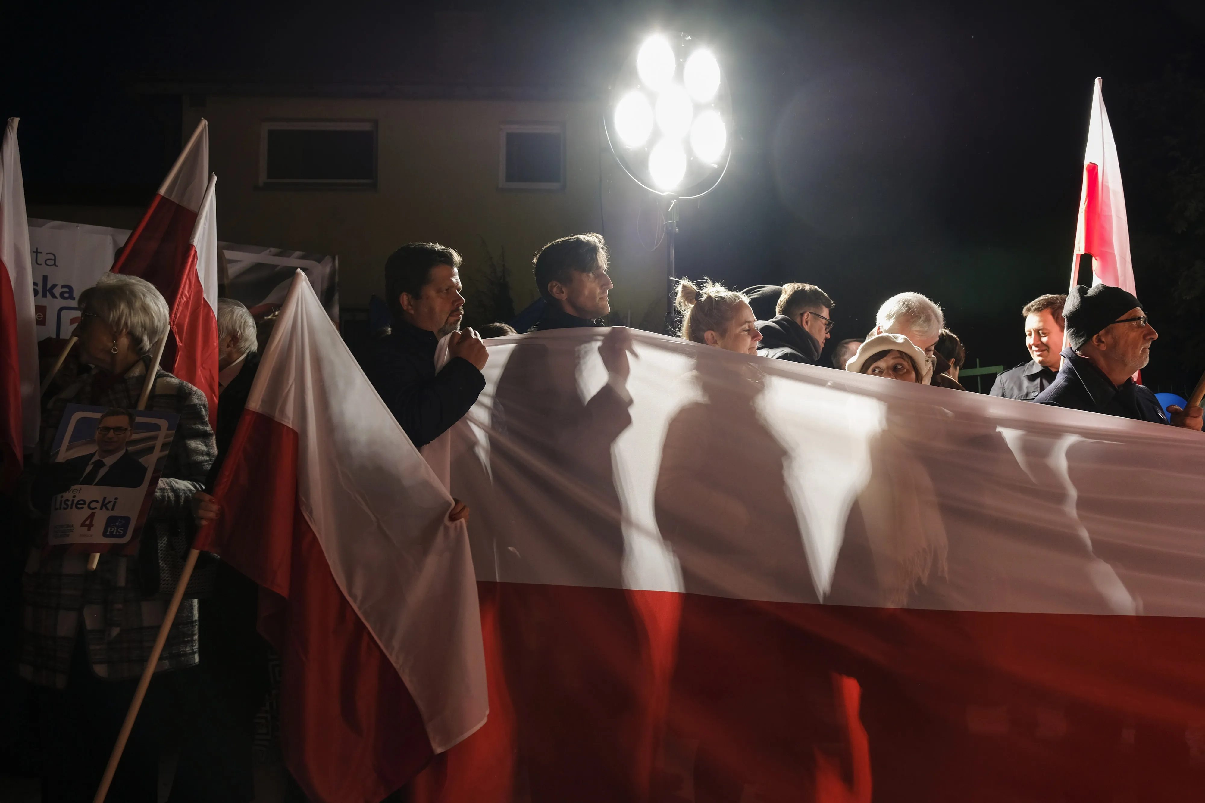 Supporters of the Law and Justice party watch an election debate on a screen outside the ATM studio in Warsaw on Oct. 9.