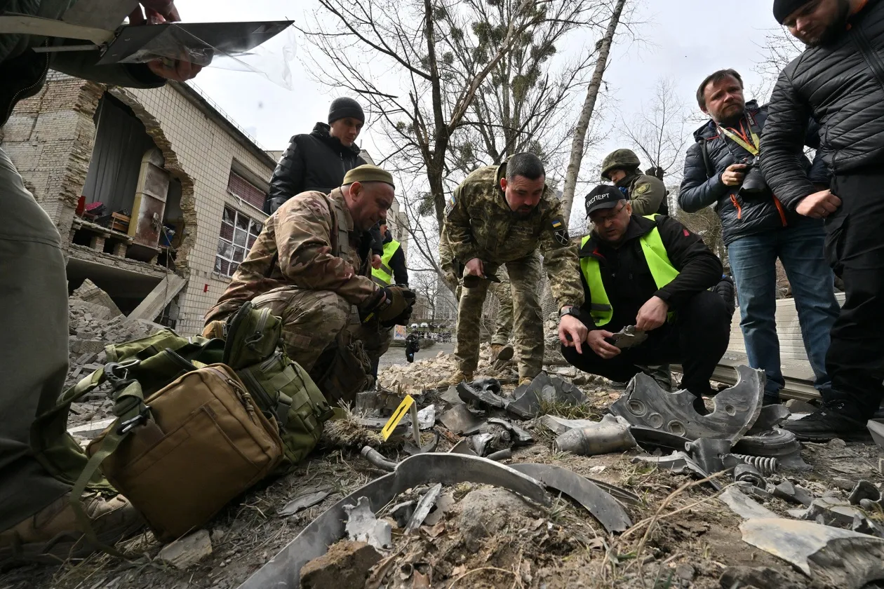 Ukrainian law enforcement officers examine fragments of a rocket at the site of a missile attack in Kyiv on March 25.