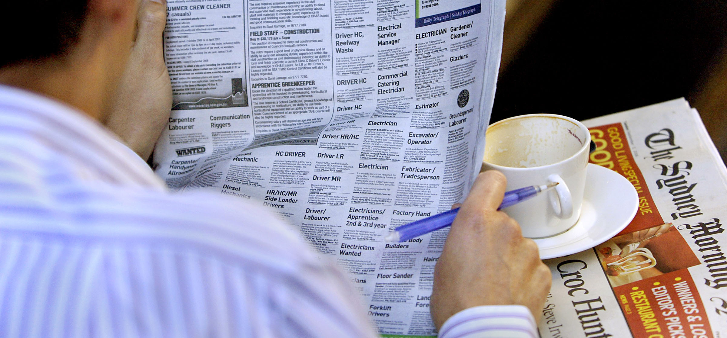 A man checks the newspaper job adverts at a cafe in Sydney, Australia, on Tuesday, September 5, 2006.  Australia's jobless rate unexpectedly fell to a 31-year low
in January as fewer people sought work, raising expectations interest rates may climb again.