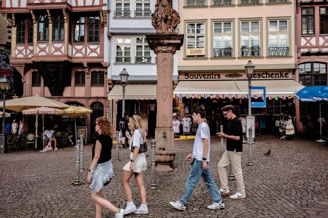 Pedestrians pass in front of a public water fountain. 