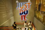 A 'Just Do It' sign is displayed on a wall as people walk down a flight of stairs in a Nike Inc. store during a media tour of the Jewel Changi Airport in Singapore.