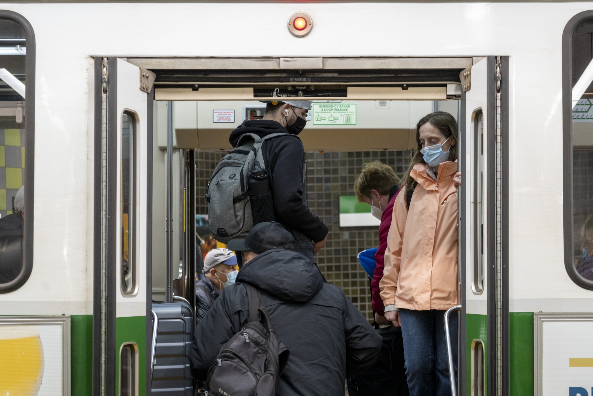 Commuters wearing protective face masks board a MBTA train&nbsp;in Boston, in April.