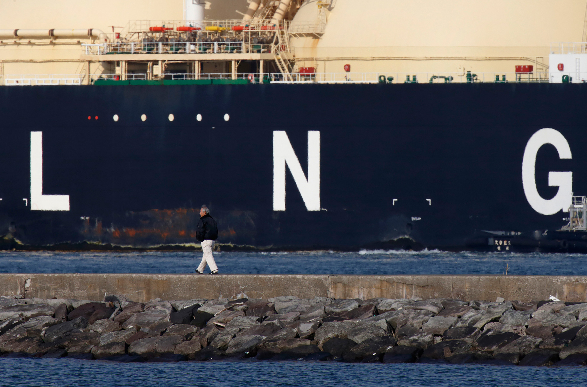 A man walks past the Shahamah liquefied natural gas (LNG) tanker sitting berthed at Tokyo Electric Power Co.'s (Tepco) Futtsu gas-fired thermal power plant in Futtsu Chiba Prefecture, Japan, on Thursday, Jan. 21, 2016. The Ministry of Finance is scheduled to release Japan's fuel trading data on Jan. 25.
