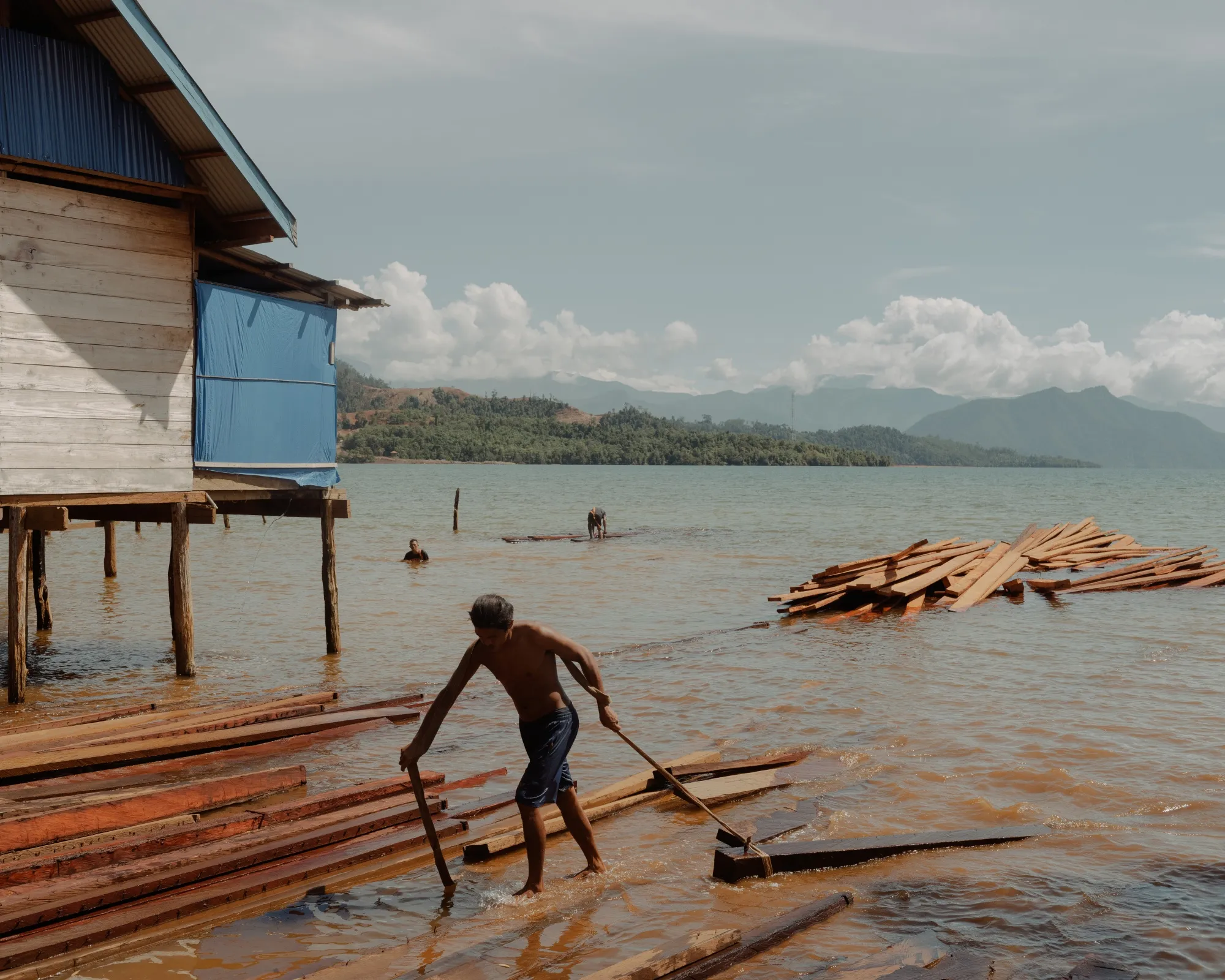 Locals take&nbsp;wood through the muddy shoreline in Ganda Ganda, not far from Kolonodale, the capital of North Morowali, Central Sulawesi. The presence of massive nickel mines nearby has destroyed the local environment.