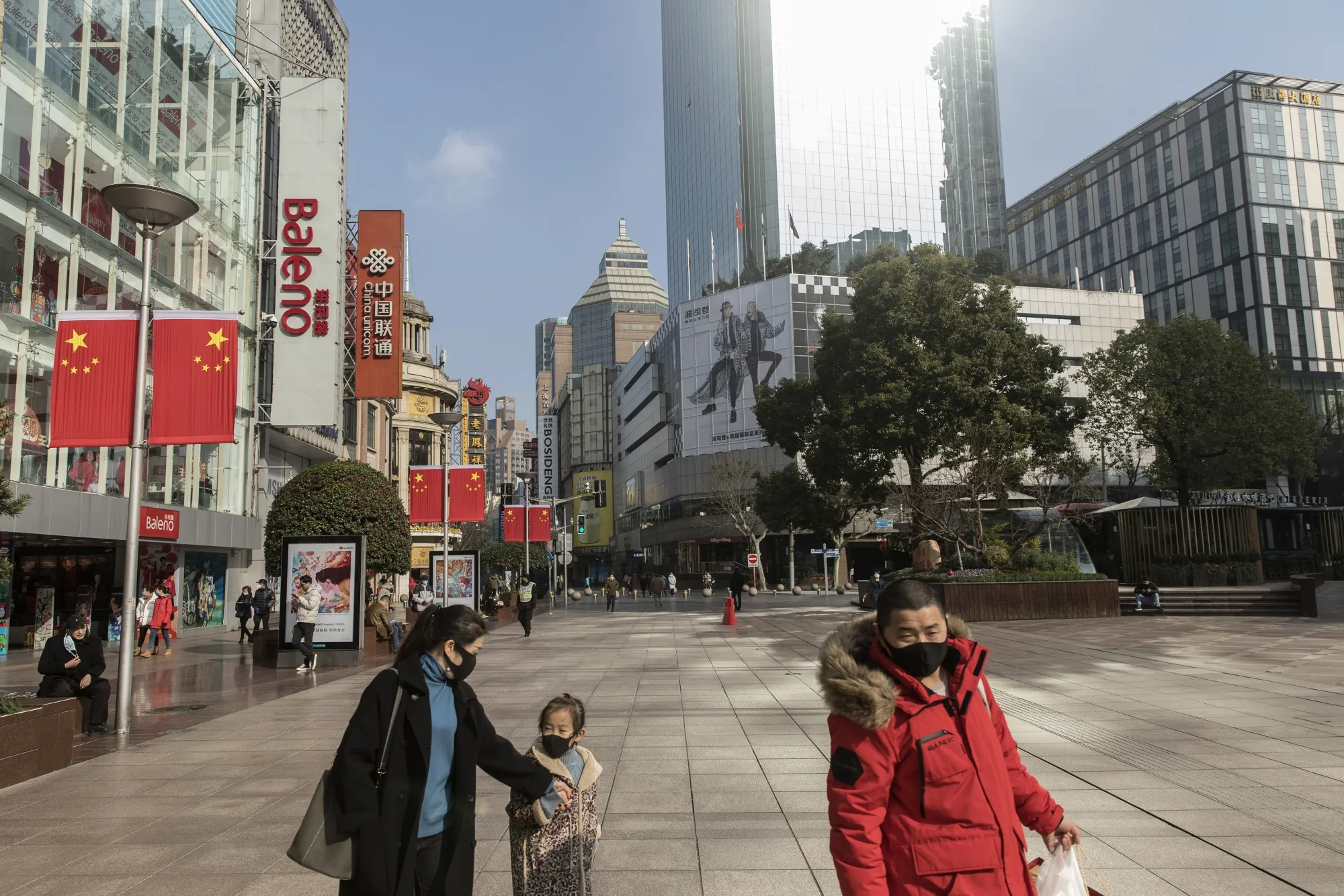 Pedestrians wearing protective masks walk past stores on Nanjing East Road in Shanghai, Jan. 30.