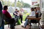 Residents chat on the porch of a home in Mosaic Commons, a cohousing community in Berlin, Massachusetts.
