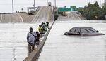 Evacuees wade down a flooded section of Interstate 610 as floodwaters from Tropical Storm Harvey rise Sunday, Aug. 27, 2017, in Houston.