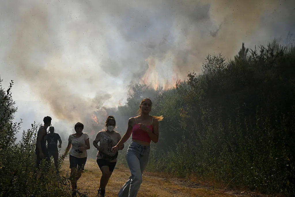 People run to escape the flames from a wildfire near the village of Melon, northwestern Spain, on Aug.&nbsp;17.