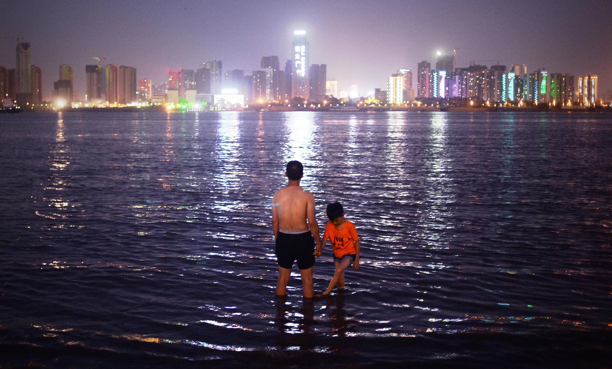 A man and child stand in the Yangtze River in Wuhan, in central China's Hubei province.