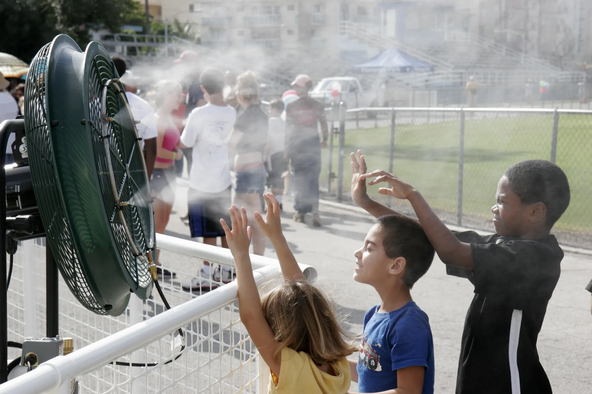 Children stand in front of a fan to cool off at Flamingo Park in Miami Beach.