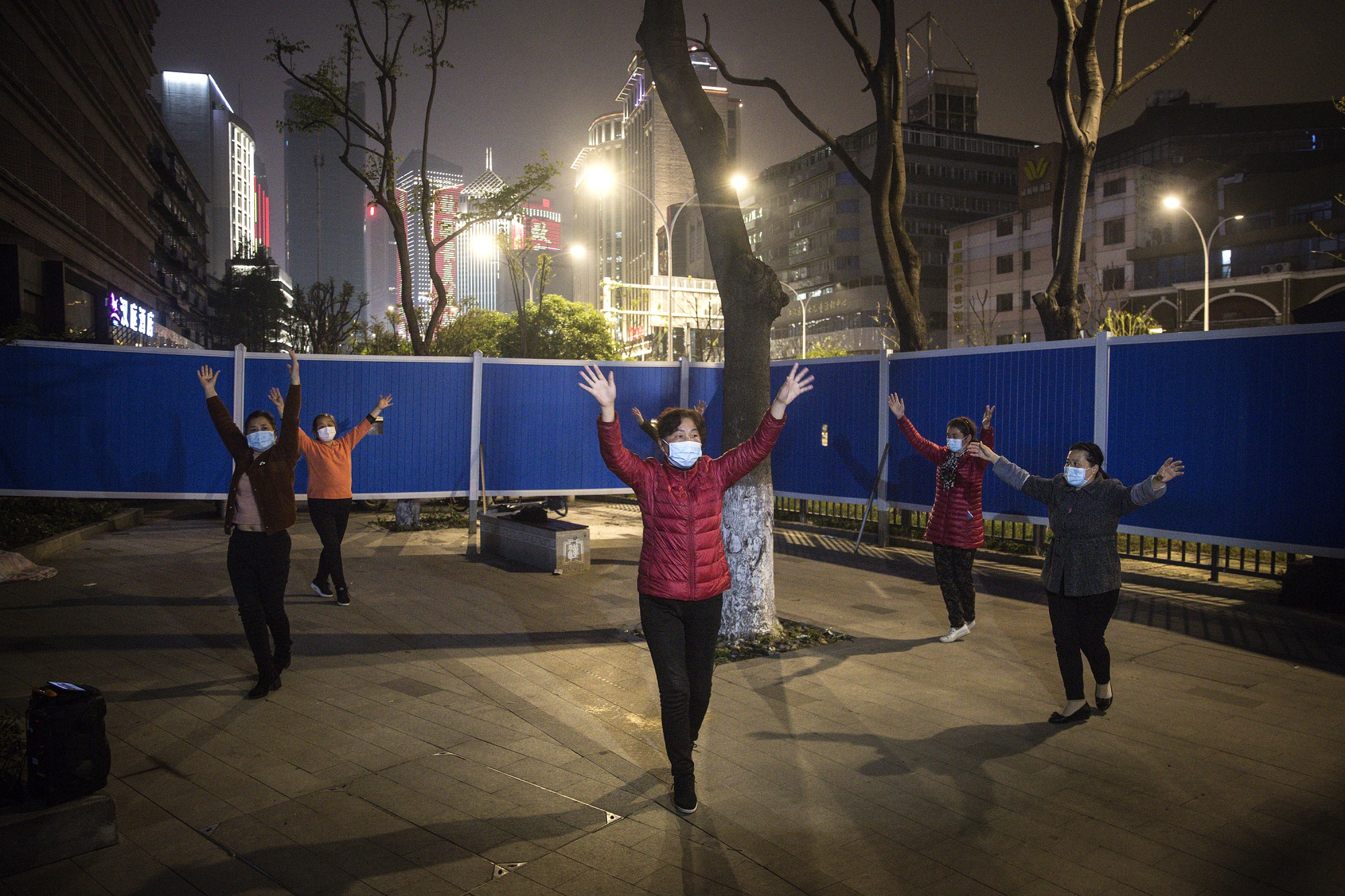 Local women dance inside a makeshift barricade wall built to control entry and exit to a residential compound at a community in Wuhan on April 2.