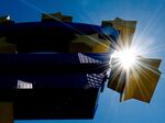 The sun shines behind German artist Ottmar Hoerl 's sculpture depicting the Euro logo outside European Central Bank.