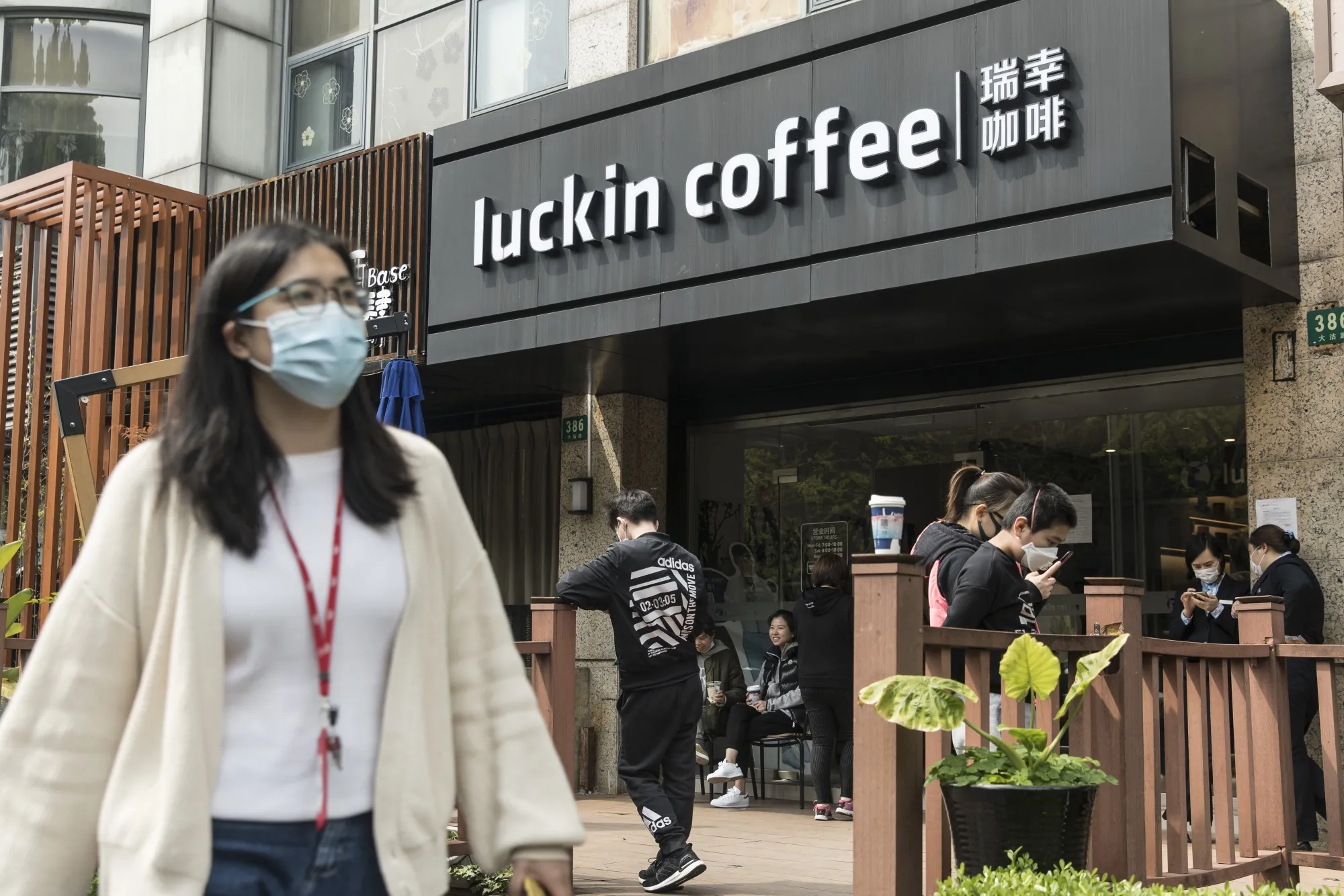 People wearing protective masks gather outside a Luckin Coffee Inc. outlet in Shanghai, on April 3.