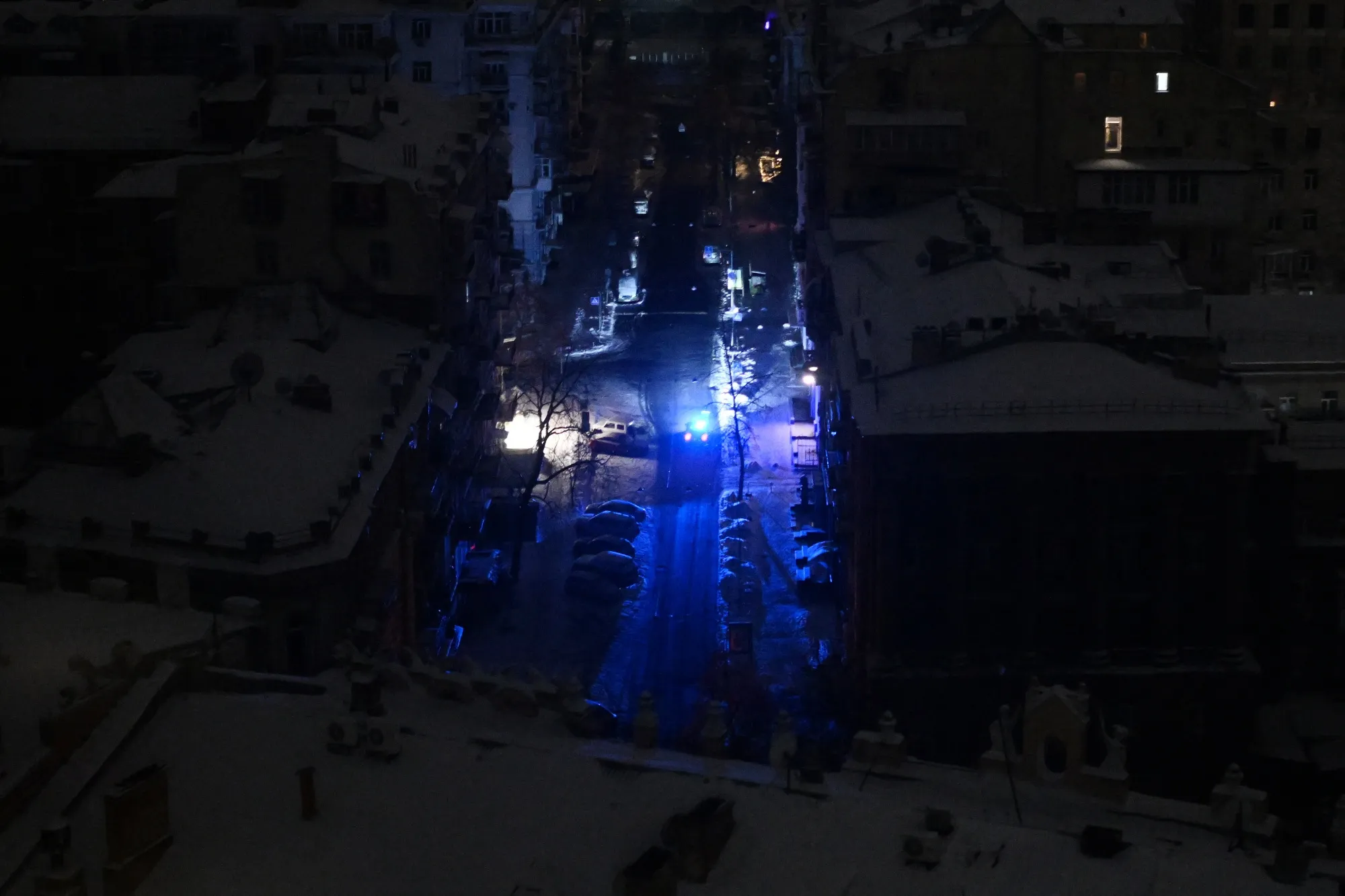 A police vehicle drives along a non-illuminated street during a power outage following an air attack in Kyiv on Jan. 24.