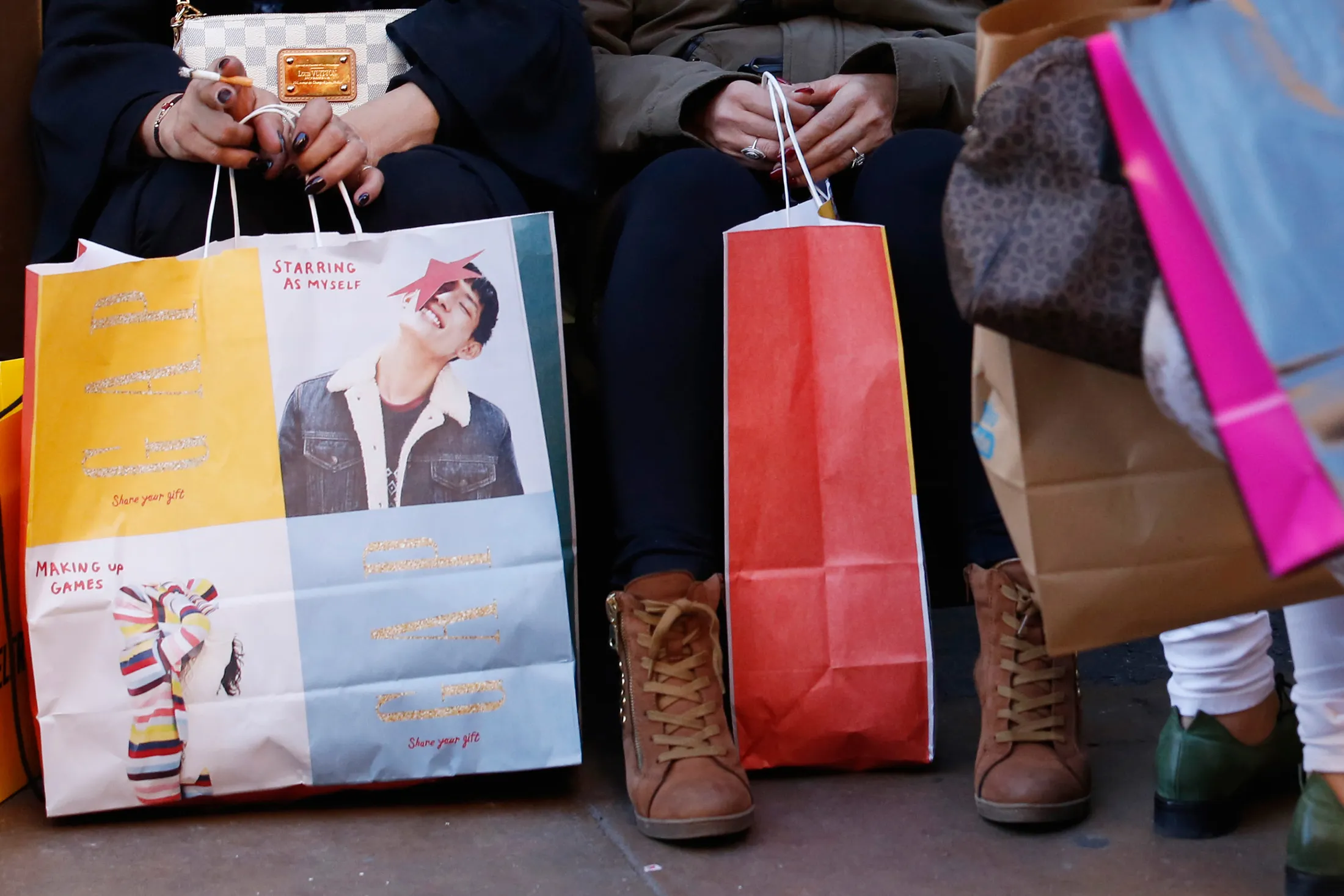 Shoppers sit and rest with multiple branded shopping bags, on Oxford Street, in London, U.K., on Friday, Nov. 25, 2016. Black Friday first became a part of U.K. shopping culture in 2014 when a rush for bargains saw fights break out as crowds gathered outside stores, in 2016 however, only 21 percent of British consumers interviewed by consultant Retail Economics said they plan to shop for Black Friday bargains.
