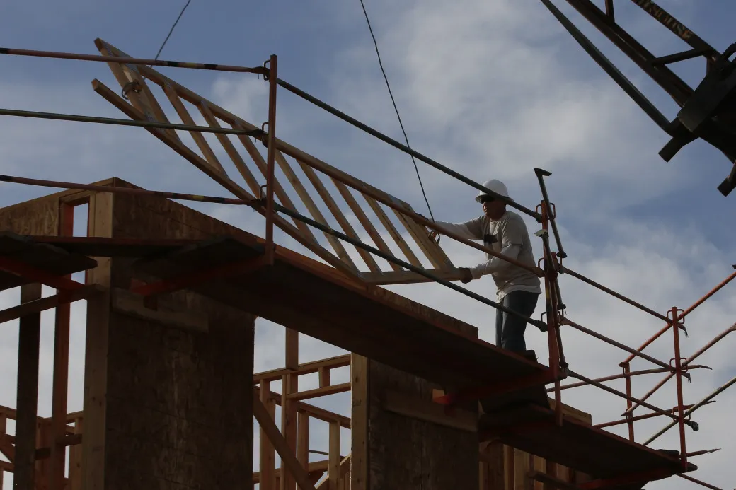 A worker guides a section of a new home as it is lifted into place at a development in Lake Forest, California.