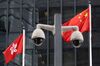 The flags of China, right, and the Hong Kong Special Administrative Region (HKSAR) are flown behind a pair of surveillance cameras outside Central Government Offices in Hong Kong, China, on Tuesday, July 7, 2020. Hong Kong leader Carrie Lam defended national security legislation imposed on the city by China last week, hours after her government asserted broad new police powers, including warrant-less searches, online surveillance and property seizures.